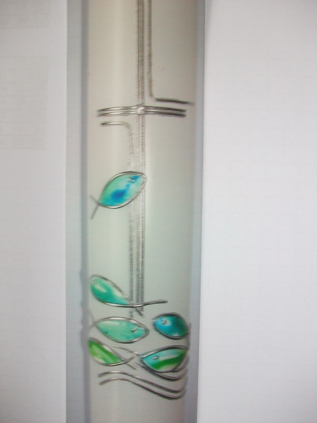 Taufkerze mit silbernem feinem Kreuz, darunter kleine Fische in pastell grün/blau